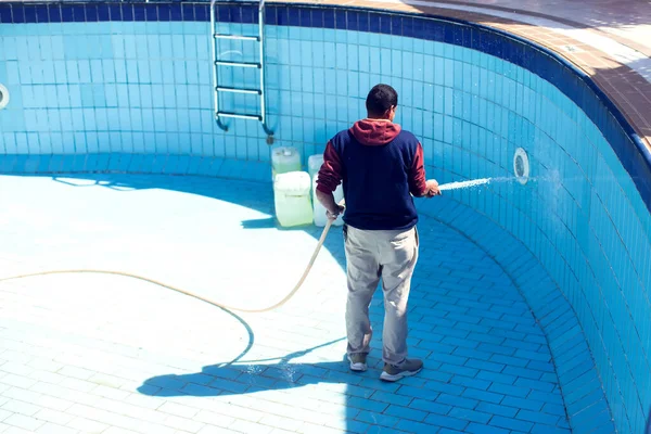 Havuzun bakımı ve bakımı. Adam havuzu temizliyor..