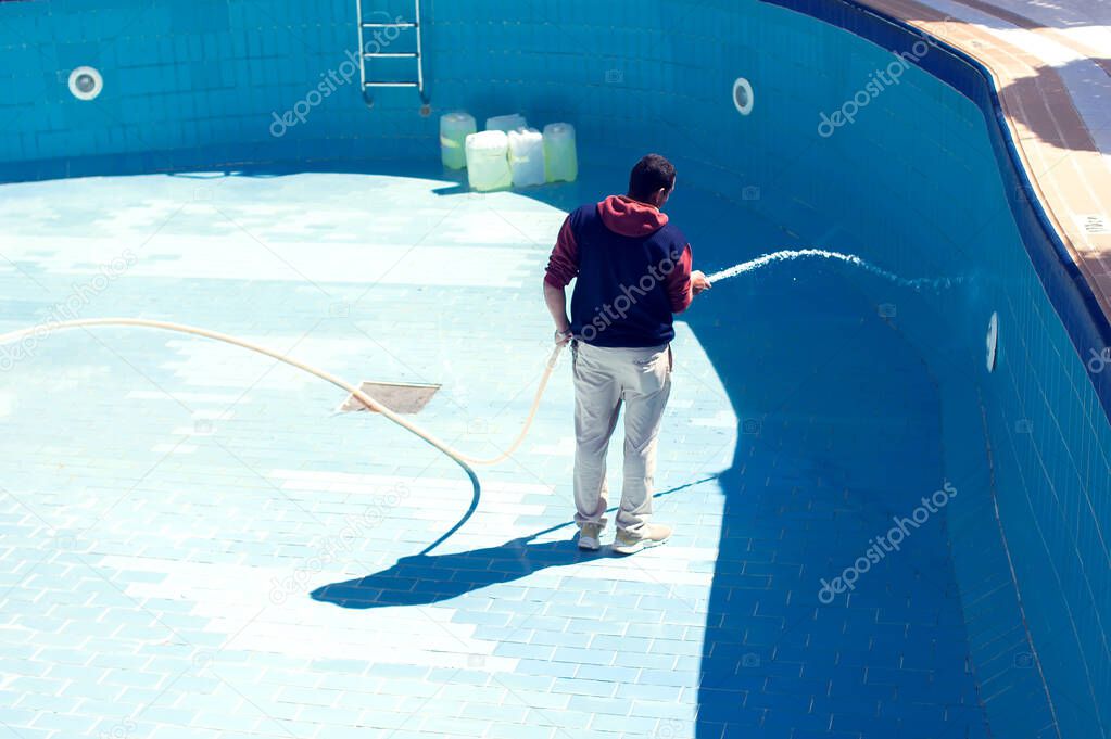 Service and maintenance of the pool. Man cleans the pool.