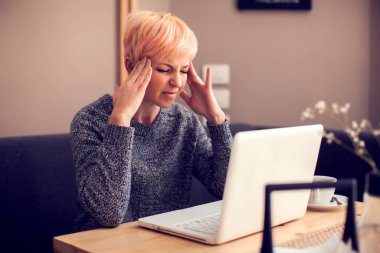 Dizüstü bilgisayarla çalışan stresli kadın baş ağrısı çekiyor. Halk, sağlık ve teknoloji kavramı
