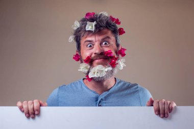 Sakalında ve saçında çiçekler olan yakışıklı, gülümseyen bir adam. İnsanlar, duygular, yaz ya da bahar konsepti