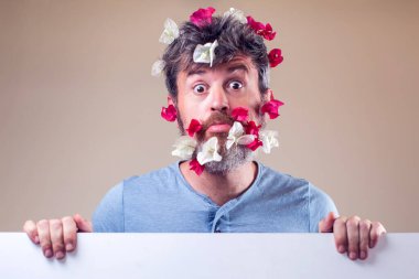 Sakalında ve saçında çiçekler olan yakışıklı, şaşkın bir adam. İnsanlar, duygular, yaz ya da bahar konsepti