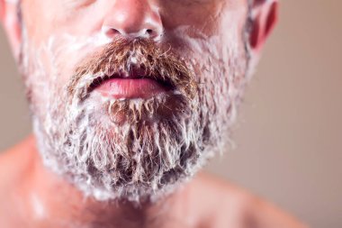 Tıraş köpüğüyle kaplı sakallı bir adamın portresi. İnsanlar ve güzellik konsepti