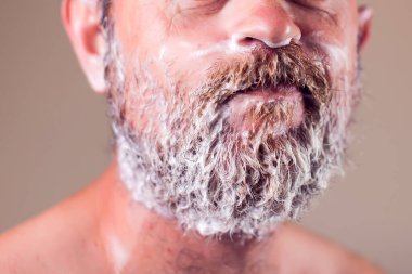 Tıraş köpüğüyle kaplı sakallı bir adamın portresi. İnsanlar ve güzellik konsepti