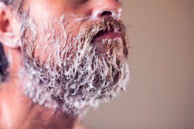 Tıraş köpüğüyle kaplı sakallı bir adamın portresi. İnsanlar ve güzellik konsepti