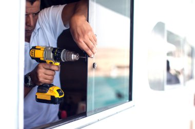 Bir adam elektrikli tornavidayla çalışıyor. .