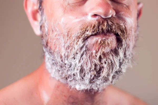 Portrait of bearded man, face covered with shaving foam. People and beauty concept