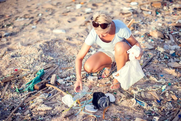 Woman collect garbage on the beach. Environmental protection concept