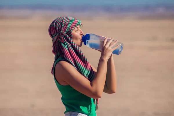 Woman drinks water in the desert of Egypt. Hot weather concept.