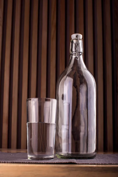 Tom Flaska Och Glas Med Vatten Över Trä Bakgrund — Stockfoto