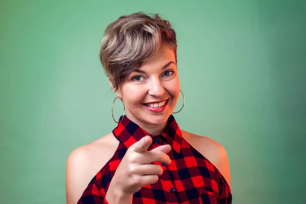 People and emotions - Happy young fashion woman with short hair posing for the camera while pointing at you.