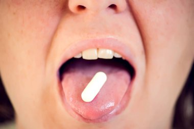 Ağzını aç ve dilinde ilaç hapını tut. İlaç alan bir kadın. Sağlık hizmetleri kavramı