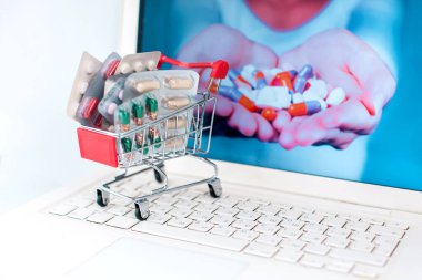 Full shopping trolley of pills at laptop on white background. Health and medicine concept. Online shopping concept clipart