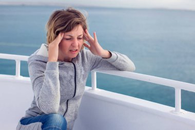 Deniz tutması geçiren turist kadın baş ağrısıyla deniz tutması geçiriyor. Seyahat ya da hastalık korkusu..