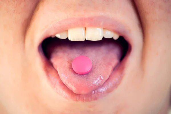 Open mouth holding medicine pill on tongue. Woman taking medicine. Healthcare concept