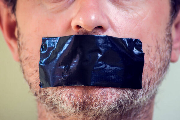 Upset man with self-adhesive tape over her mouth.