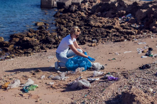 티셔츠를 커다란 파란색 가방을 해변에서 쓰레기를 모으는 봉사를 있습니다 — 스톡 사진