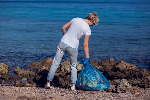 女志愿者穿着白色T恤 蓝色大包 在海滩上捡垃圾 环境污染概念 — 图库照片