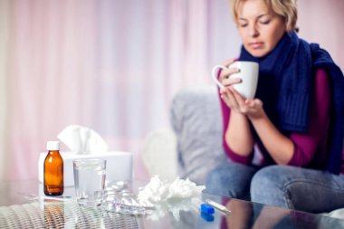 Kısa sarı saçlı kadın grip oldu ve evde sıcak çay içiyor. Halk, sağlık ve tıp konsepti