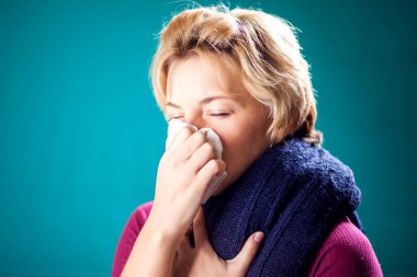 Kısa sarı saçlı kadın nezle olmuş ve burnunu peçeteye sümkürmüş. Halk, sağlık ve tıp konsepti