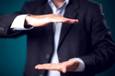 Businessman in suit holding something invisible in hands in front of black background