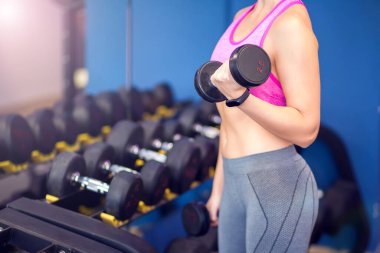 Woman in pink top and short blond hair doing workout with dumbbells. People, fitness and health care concept