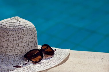 White hat and sunglasses lying beside pool. Summer and holiday concept