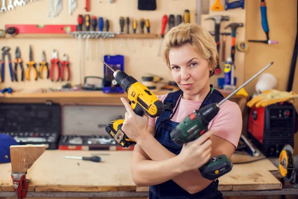 Young smiling handy woman with short blond hair working with screwdriver.