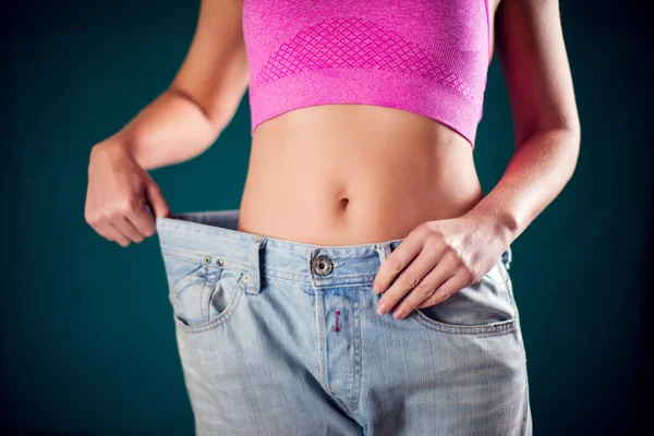 Woman wearing big size jeans. Weight loss, fitness and diet concept