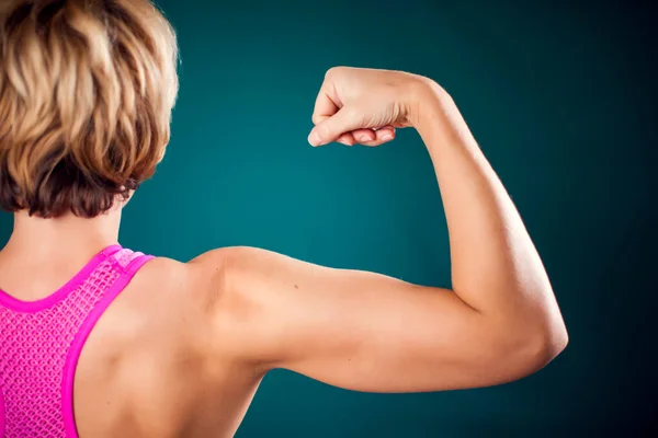Woman with fit arm showing triceps and bicep. People, fitness and health concept