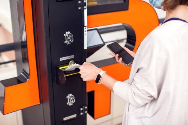 Bitcoin ATM. Şifreli para almak ya da satmak için Bitcoin ATM kullanan bir kadın. Elektronik para birimi
