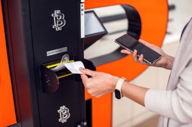 Bitcoin ATM. Şifreli para almak ya da satmak için Bitcoin ATM kullanan bir kadın. Elektronik para birimi