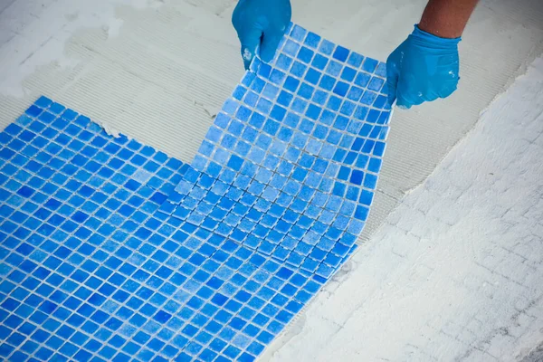 Worker laying tile in the pool. Pool repairing work.