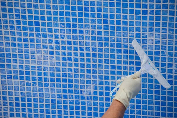 Pool renovation work. A worker lays the tiles and covers the seams in the pool