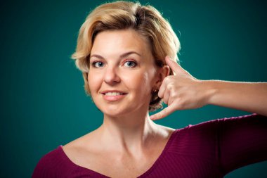 Kısa sarı saçlı, telefon işareti yapan bir kadın. İnsanlar, yaşam tarzı ve iletişim konsepti