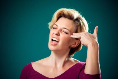 Kısa sarı saçlı kadın parmaklarıyla silah hareketi yapıyor. İnsanlar, yaşam tarzı ve duygu kavramı