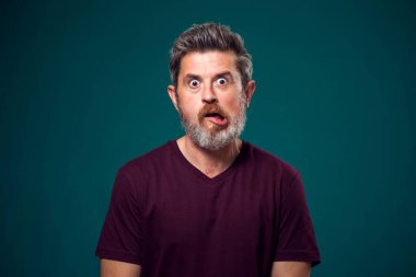 Kırmızı tişörtlü, sakallı, şaşırmış bir adamın portresi. İnsanlar ve duygular