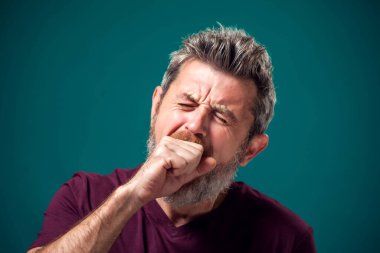 Kırmızı tişörtlü, esneyen, sakallı, sıkılmış bir adamın portresi. İnsanlar ve duygular