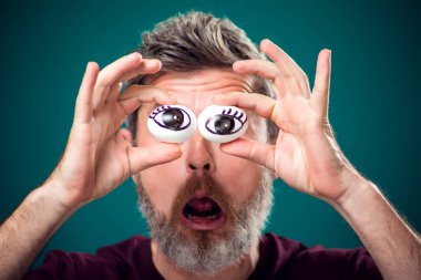 Gözlerinin arkasında yumurta tutan kırmızı tişörtlü komik sakallı adamın portresi. İnsanlar, duygular ve yemek konsepti