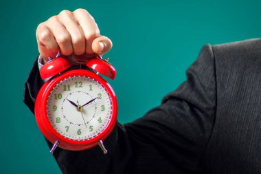 Sakallı iş adamı elinde kırmızı alarm saati tutuyor. Zaman yönetimi kavramı