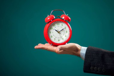 Sakallı iş adamı elinde kırmızı alarm saati tutuyor. Zaman yönetimi kavramı