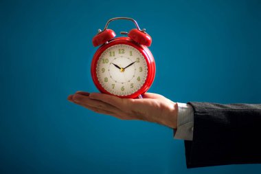 Sakallı iş adamı elinde kırmızı alarm saati tutuyor. Zaman yönetimi kavramı