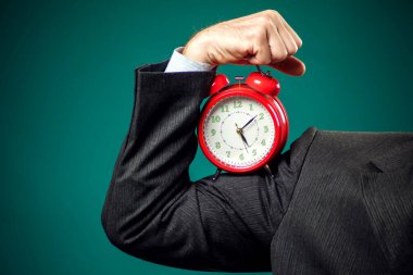 Sakallı iş adamı elinde kırmızı alarm saati tutuyor. Zaman yönetimi kavramı