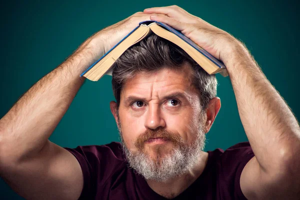 赤いTシャツを着た髭の男の肖像画が頭の上に本を開いた 検索の概念 — ストック写真