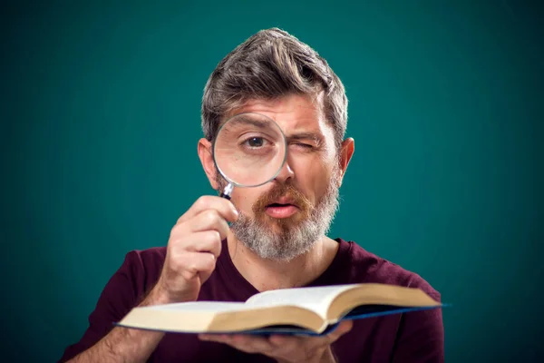 赤いTシャツを着た髭の男の肖像画が本を開き 虫眼鏡をかけた 検索の概念 — ストック写真