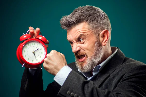 赤い目覚まし時計を保持し それを叫んで訴訟で怒ってひげを生やしたビジネスマン 時間管理の考え方 — ストック写真