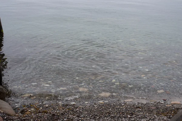 Ondulations d'eau sur la côte avec des pierres de galets — Photo