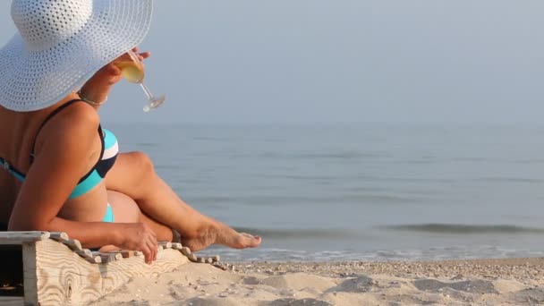 Beautiful girl in a hat on a lounger drinking wine — 图库视频影像