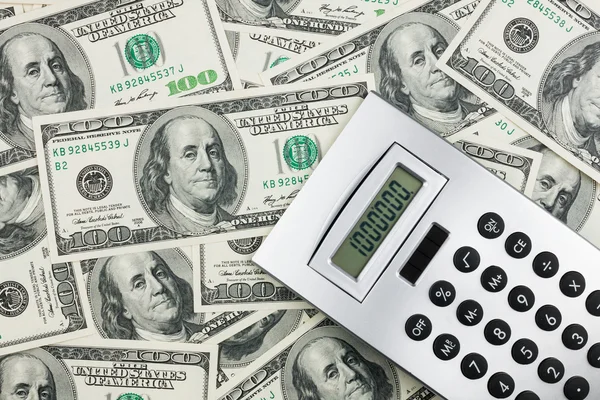 Calculator lying on a background of dollars — Stok fotoğraf