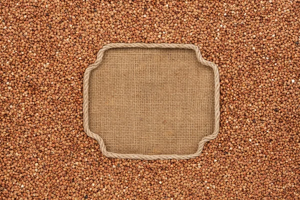 Figured frame made of rope with buckwheat grains on sackcloth — Stock Photo, Image