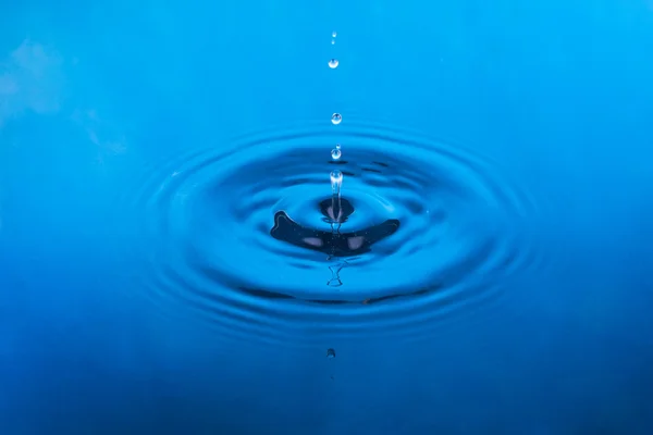 Falling drop of water in blue water — Stock Photo, Image